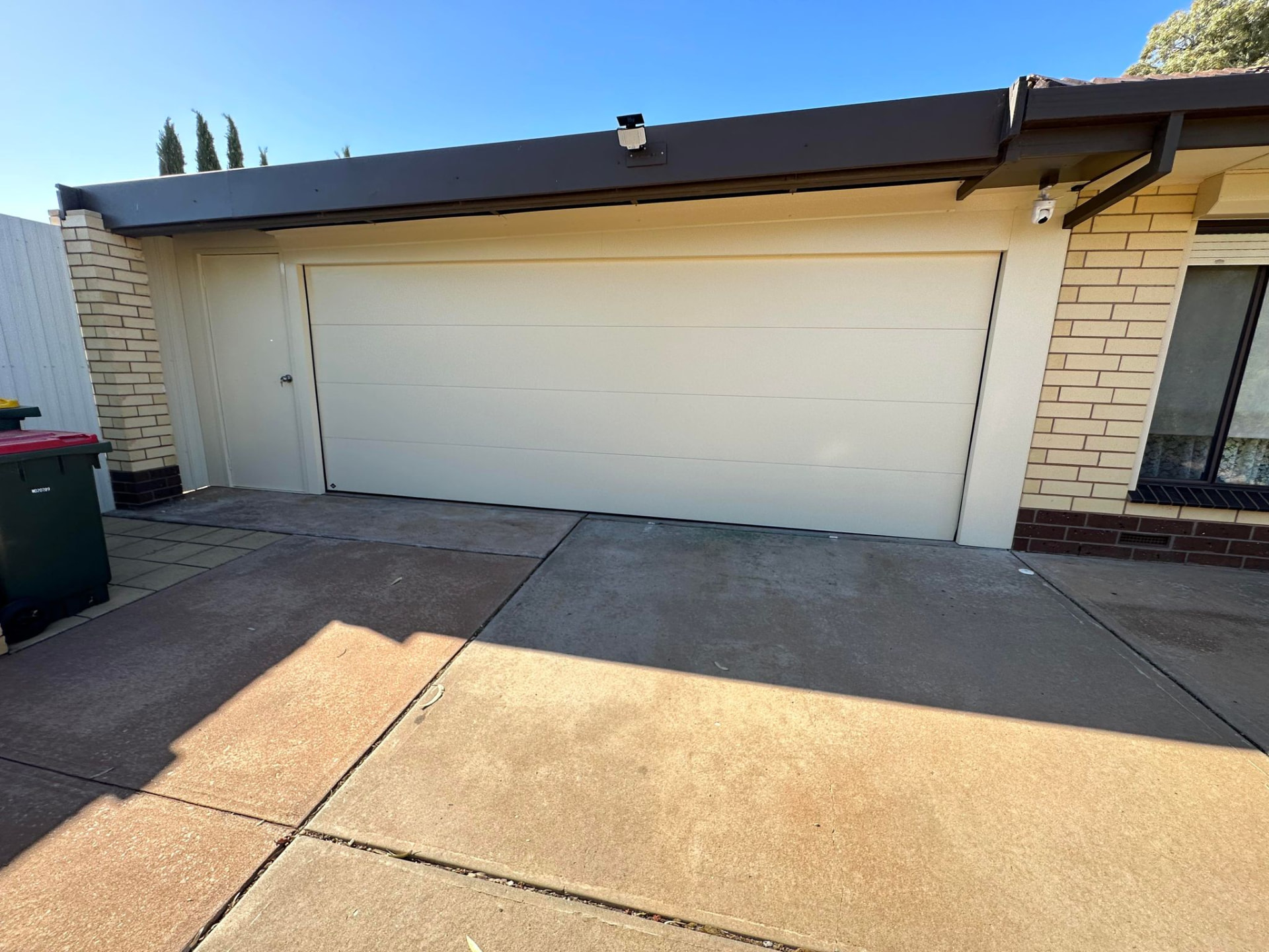 Cream flat-profile sectional garage door beside a matching side access door