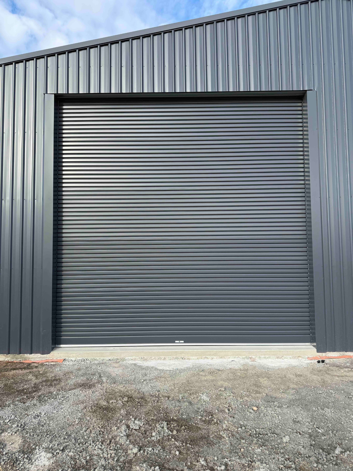Exterior view of a dark-coloured B&D R2I industrial roller door installed in a commercial building façade