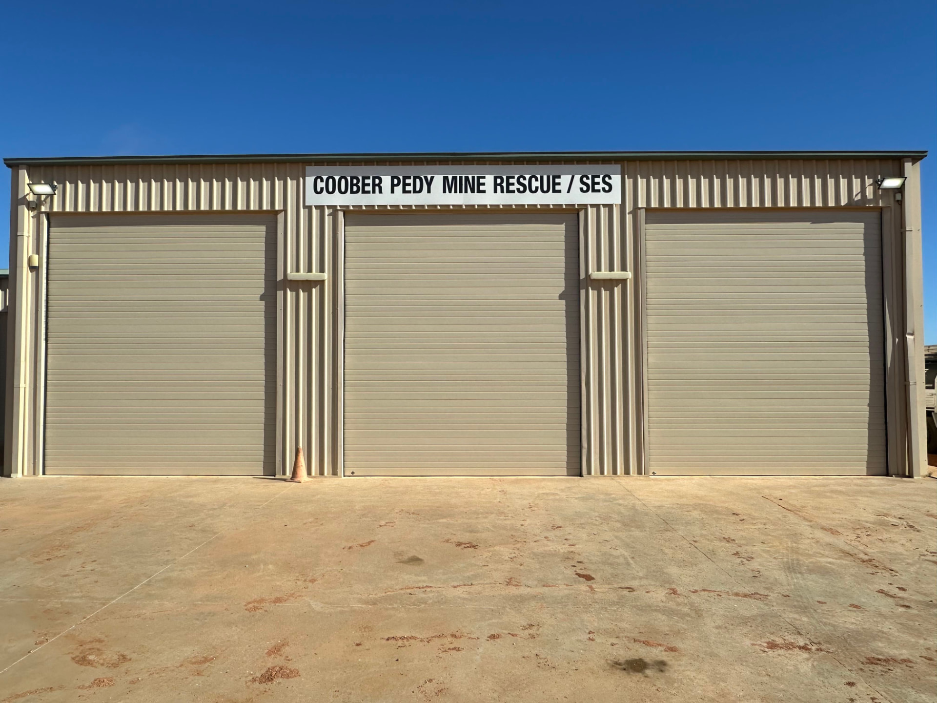 Three Paperbark B&D Panel Lift doors installed across a commercial facility with a Coober Pedy Mine Rescue / SES sign above