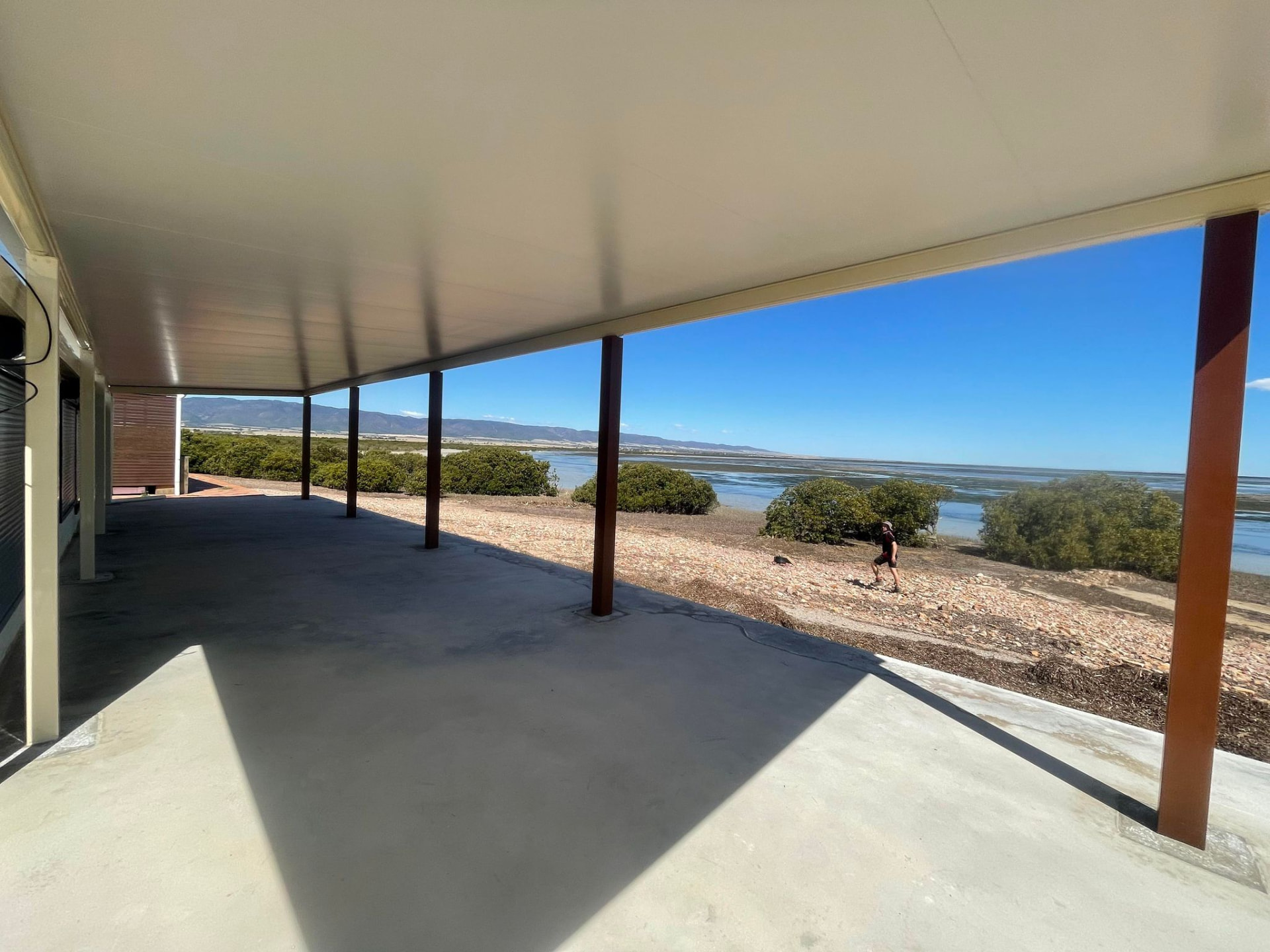 Wide flat-roof verandah over a concrete slab overlooking mangroves and water