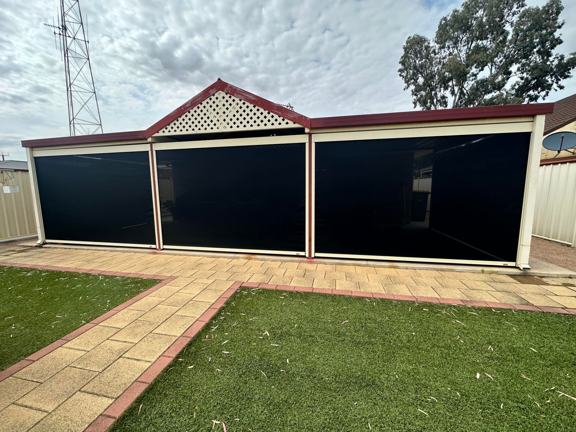 Three dark outdoor blinds lowered across a cream verandah