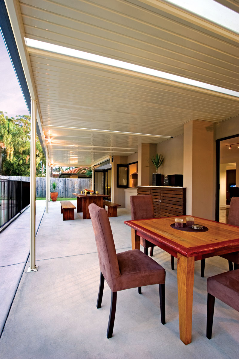 Attached Stratco Outback flat-roof verandah with translucent infill sheeting over an outdoor dining area — Stratco product imagery