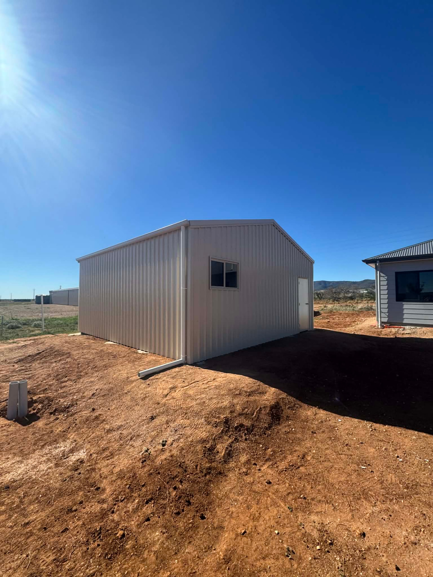 Completed cream steel shed with a personnel access door and side window