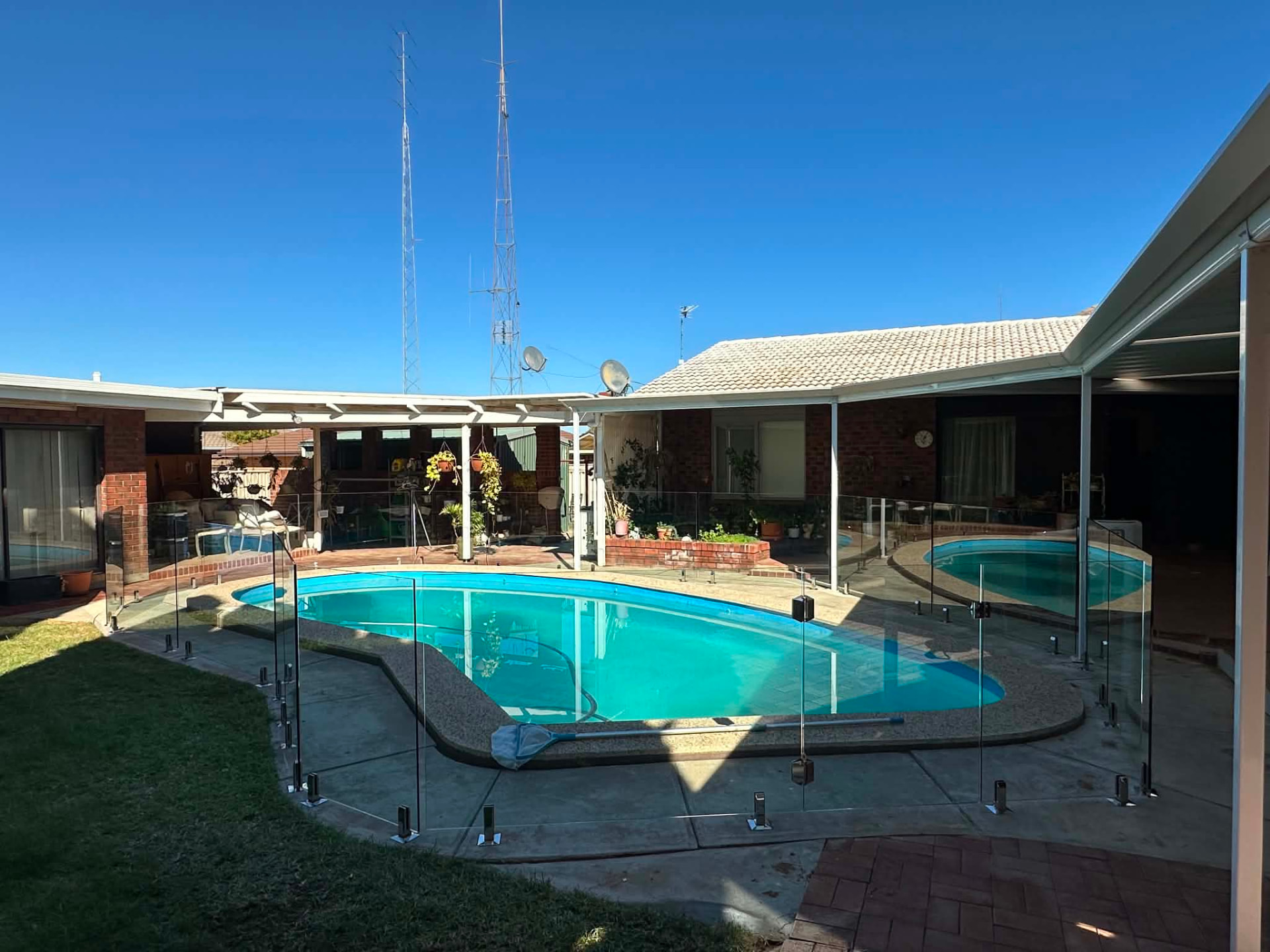 Frameless glass pool fence panels installed along a pool edge