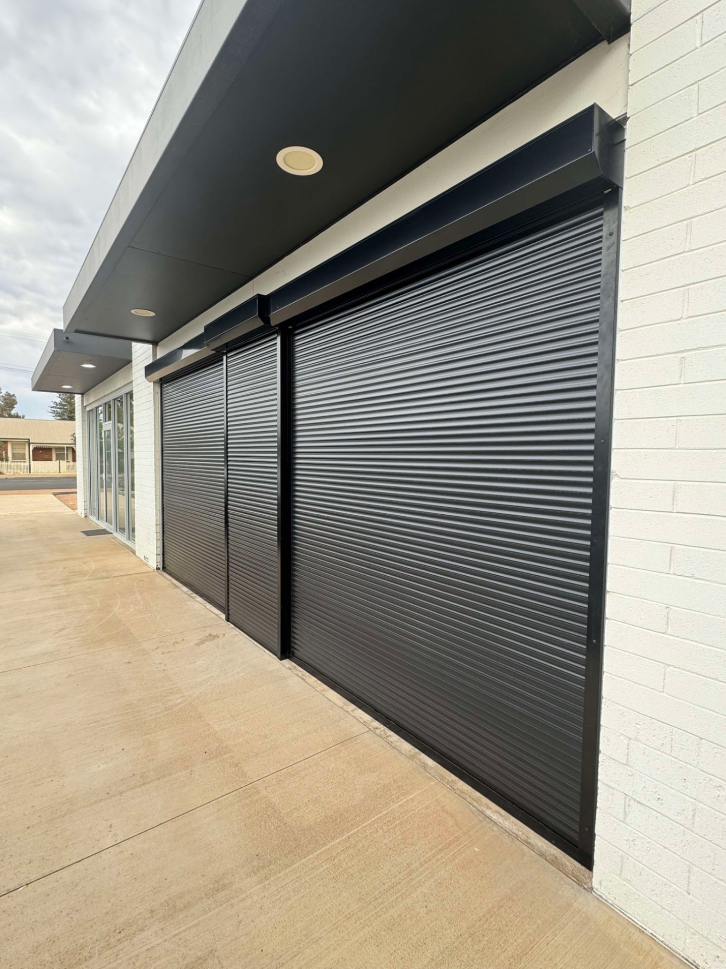 Three black commercial roller shutters closed across a shopfront