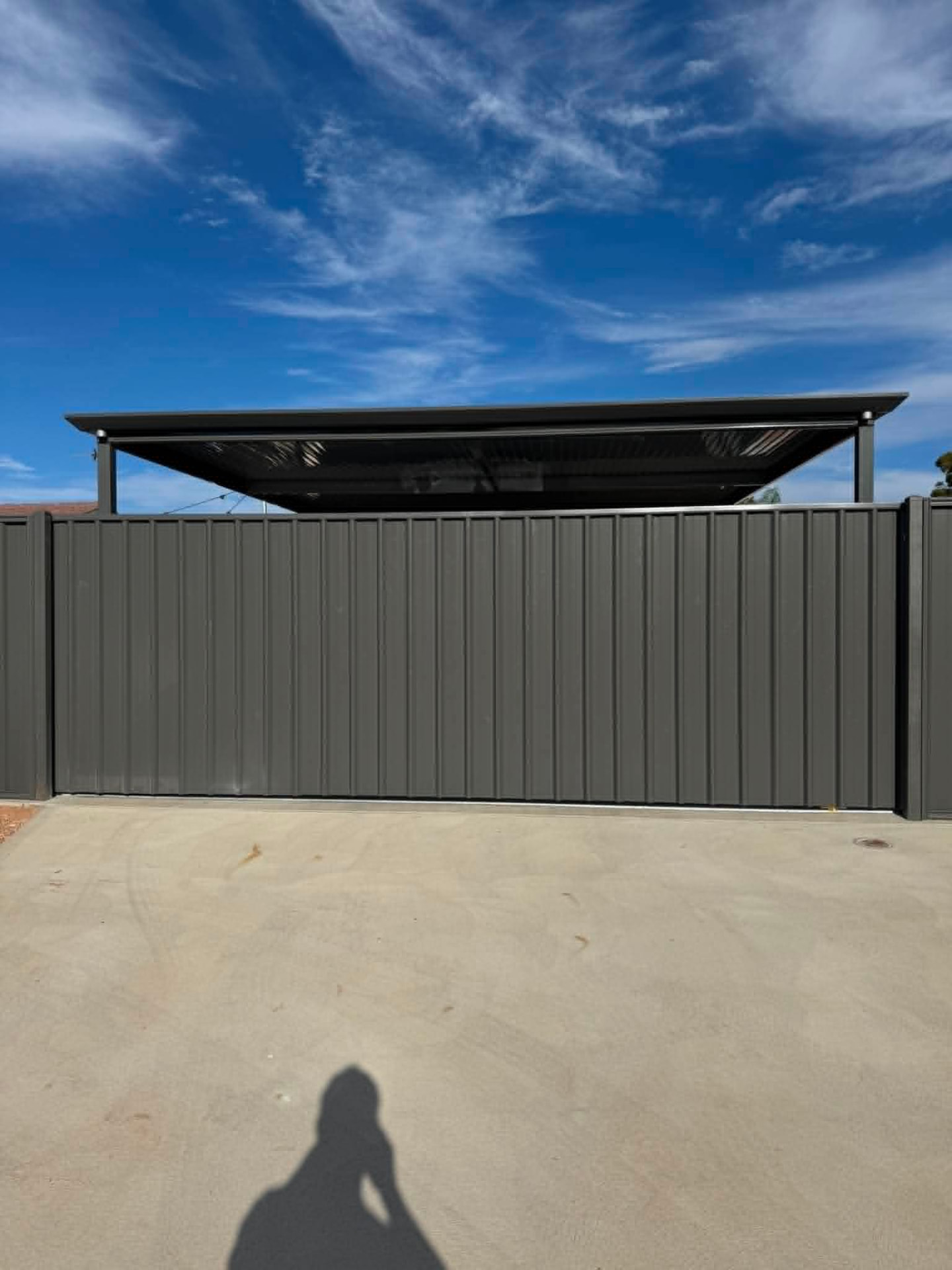 Charcoal custom-built sliding driveway gate closed across a concrete driveway