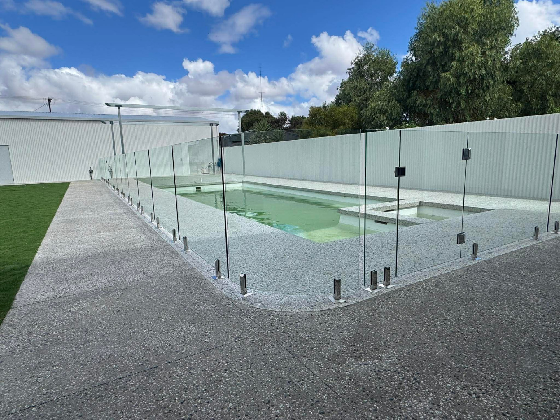 Curved frameless glass pool fence following the edge of a swimming pool